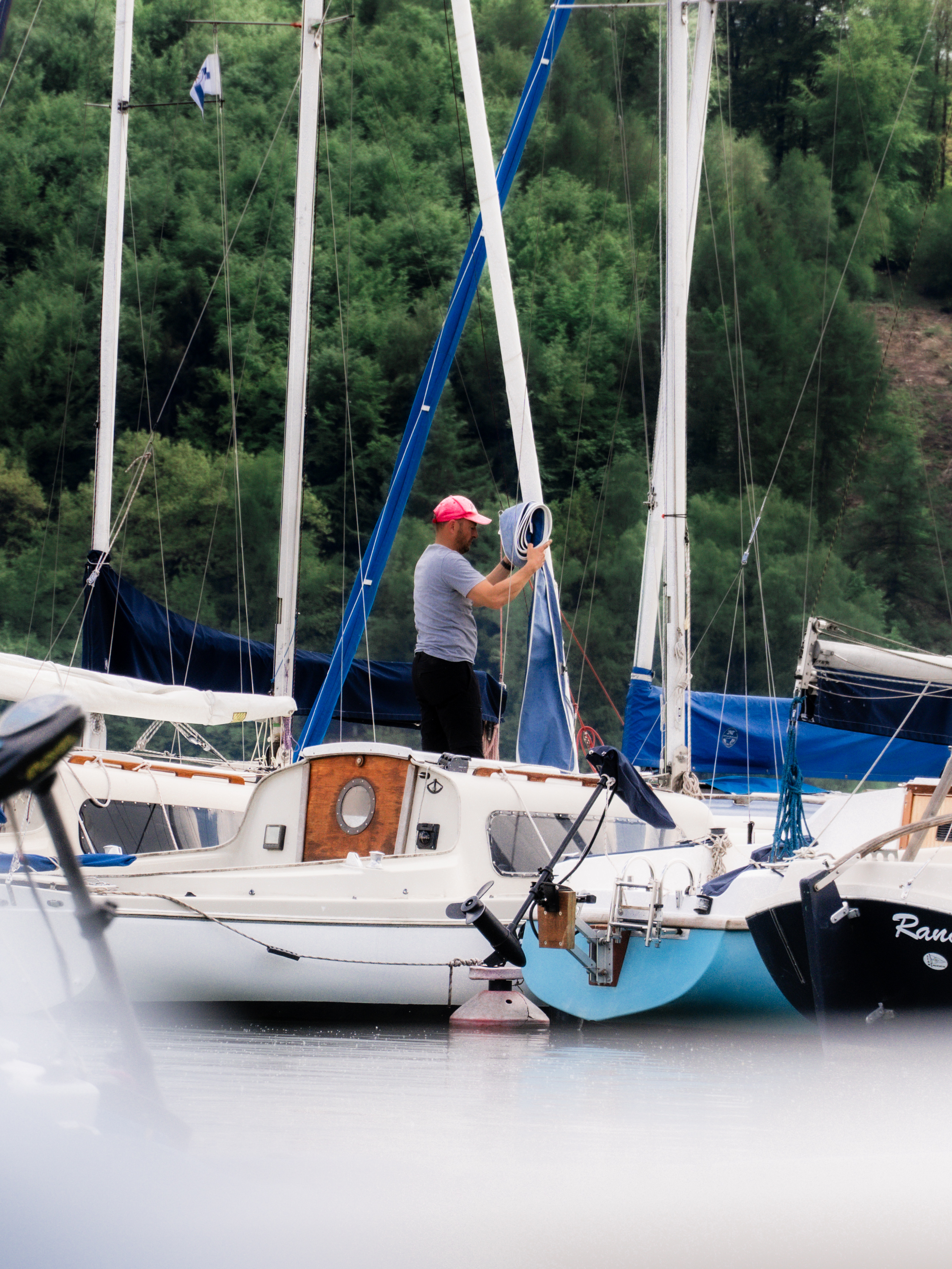 Segler rollt ein Segel im Hafen auf