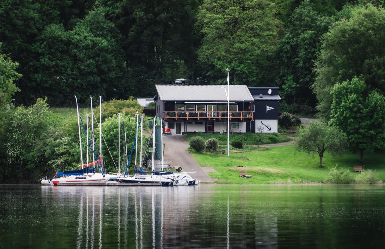 Clubhaus des SCHM vom Wasser aus gesehen, davor die Steganlage mit Segelbooten